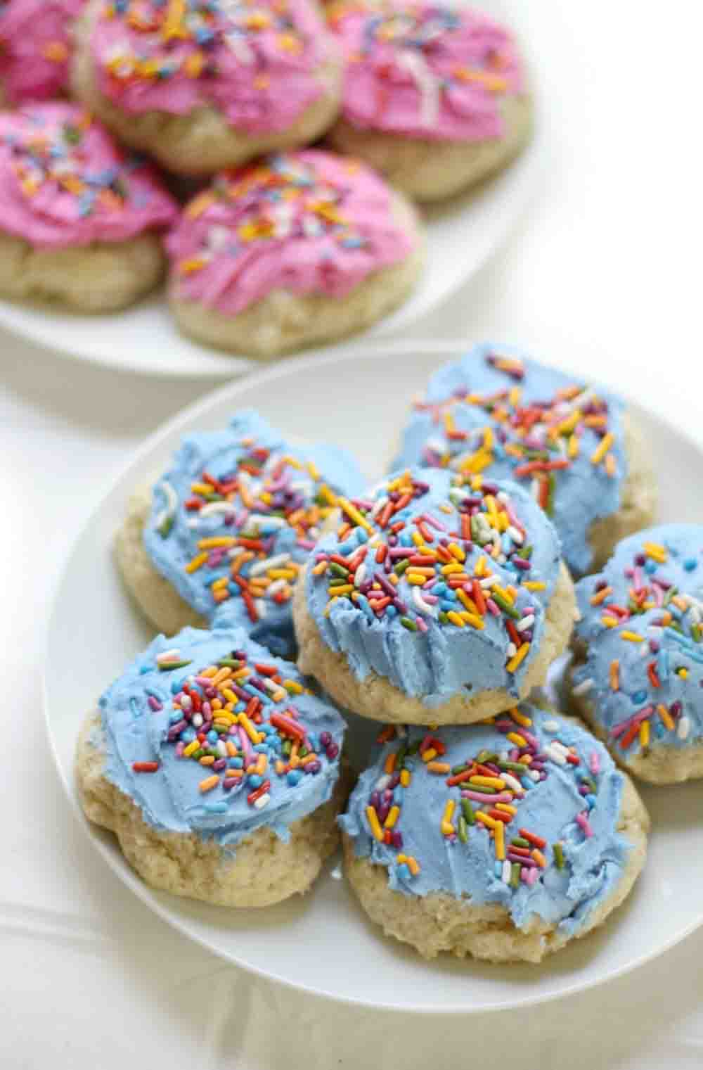 Frosted sugar cookies with pastel pink and blue icing, decorated with rainbow sprinkles.