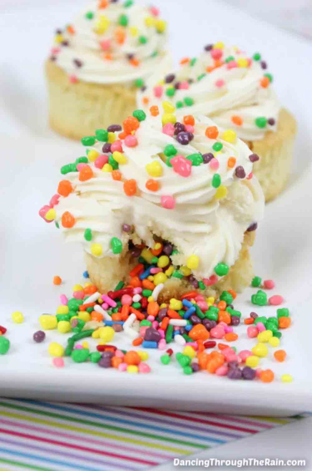 Vanilla cupcakes filled with candy and topped with sprinkles, perfect as DIY baby shower desserts that surprise guests.