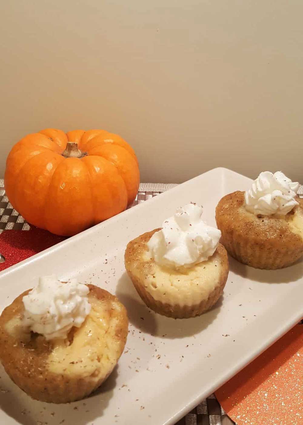 Homemade baby shower desserts featuring mini pumpkin cheesecake bites with whipped cream and cinnamon on top.