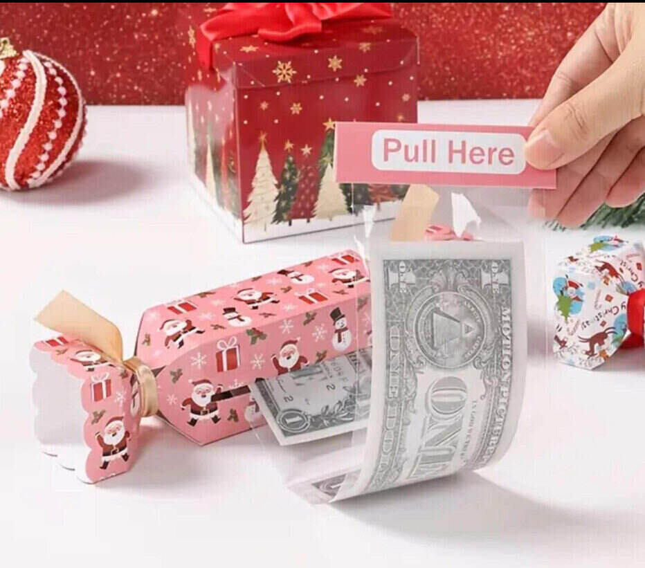 pink candy wrapper style box with Santa Claus pattern on and a slit on the side where you can pull out dollar bills encased in plastic wrapping.