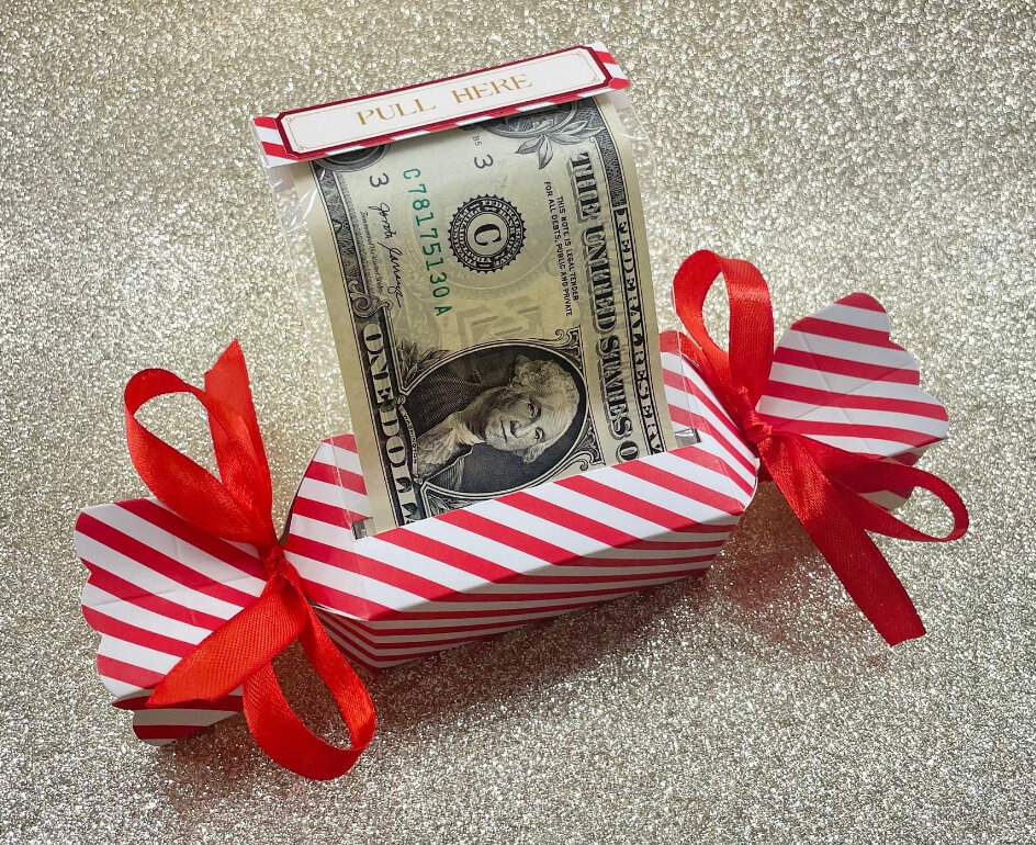 red & white candy wrapper style box with red ribbons and a slit on the side where you can pull out dollar bills