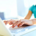 teenage girl holding hands over a laptop keyboard