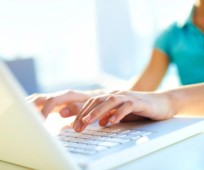 teenage girl holding hands over a laptop keyboard