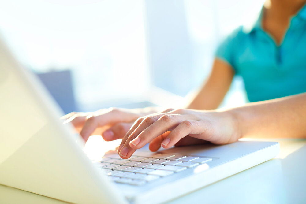 teenage girl holding hands over a laptop keyboard