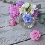 colorful flower arrangement in a glass vase sitting on a wood background