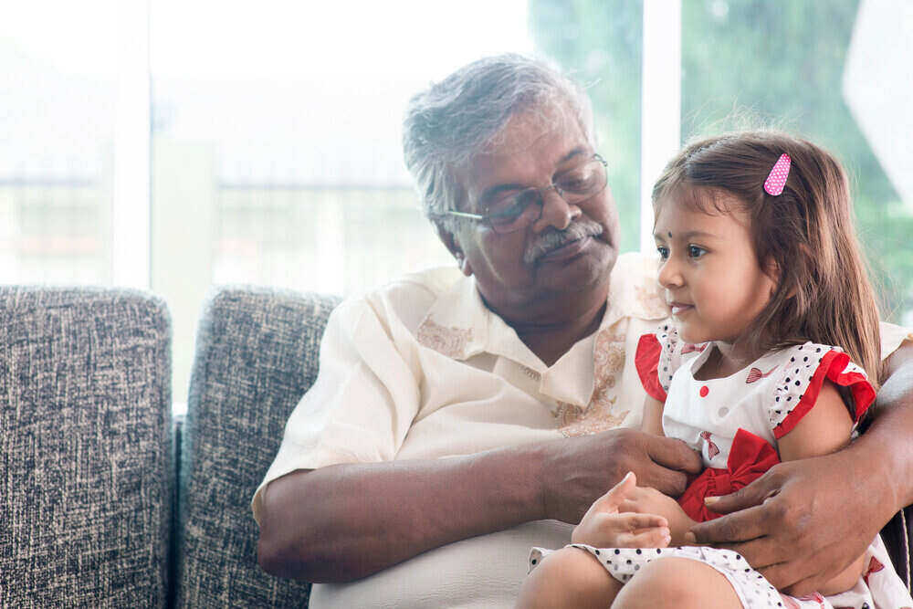 grandpa holding granddaughter while sitting on a couch