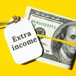 roll of 100 dollar bills with a tag that says extra income next to it on a yellow background