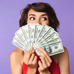 woman holding money fanned out in front of her face