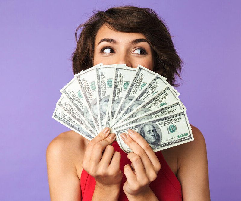 woman holding money fanned out in front of her face
