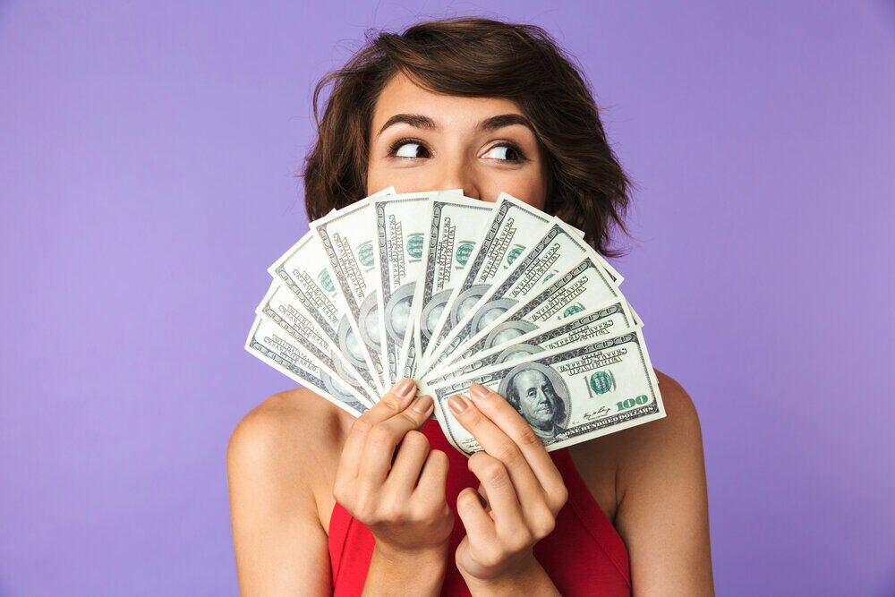 woman holding money fanned out in front of her face